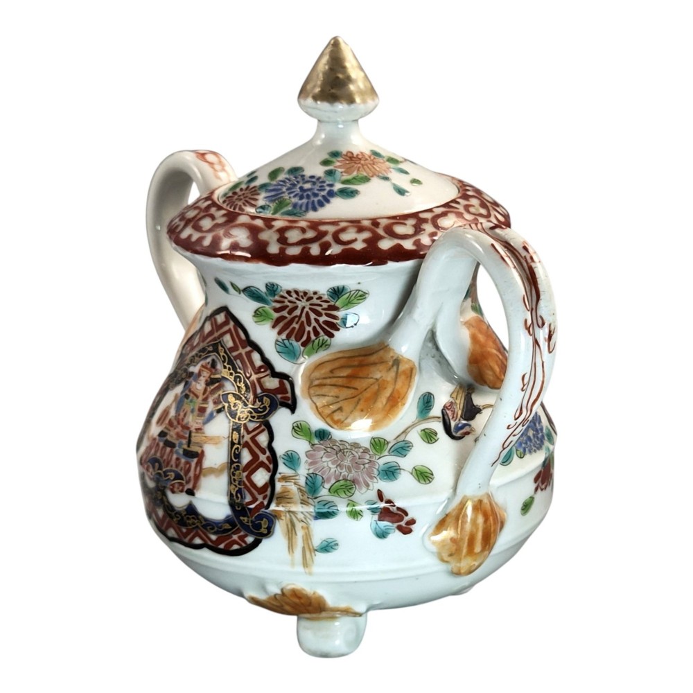 A covered Japanese Imari porcelain sugar bowl featuring double side handles, a pointed gilded finial, and hand-painted samurai and floral motifs in red, blue, green, and gold enamels. View II