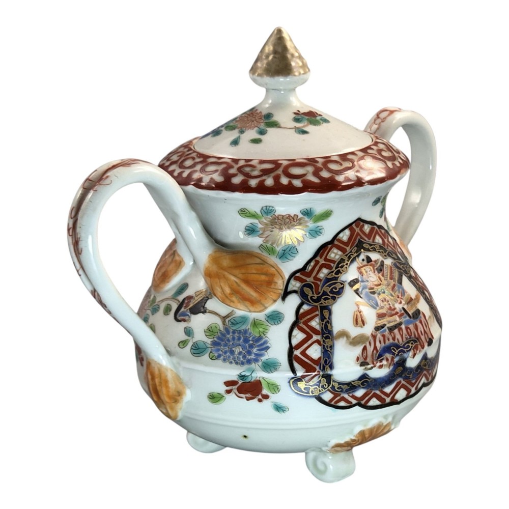 A covered Japanese Imari porcelain sugar bowl featuring double side handles, a pointed gilded finial, and hand-painted samurai and floral motifs in red, blue, green, and gold enamels. View III