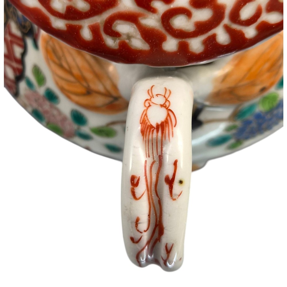 A covered Japanese Imari porcelain sugar bowl featuring double side handles, a pointed gilded finial, and hand-painted samurai and floral motifs in red, blue, green, and gold enamels. View X