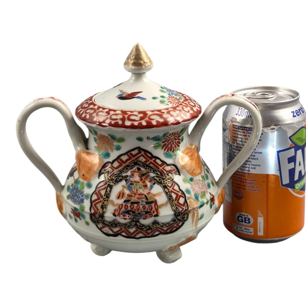 A covered Japanese Imari porcelain sugar bowl featuring double side handles, a pointed gilded finial, and hand-painted samurai and floral motifs in red, blue, green, and gold enamels. View XIII
