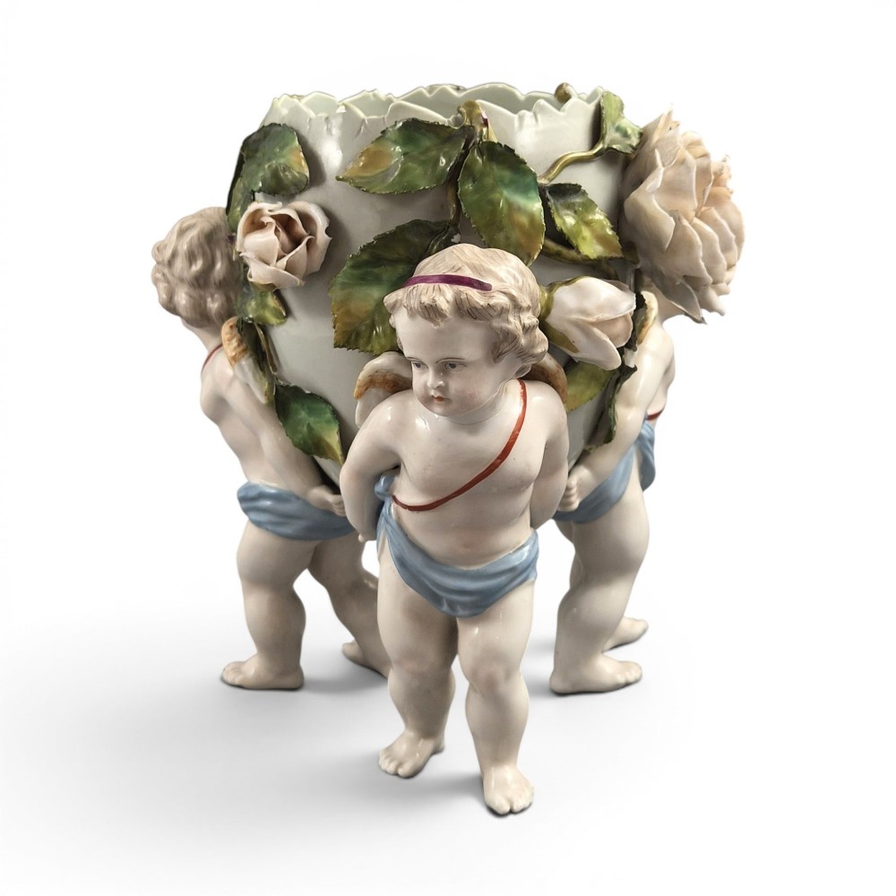 A German Sitzendorf porcelain egg-shaped vase featuring applied green leaves, pale pink roses, and three cherub figures supporting the base.