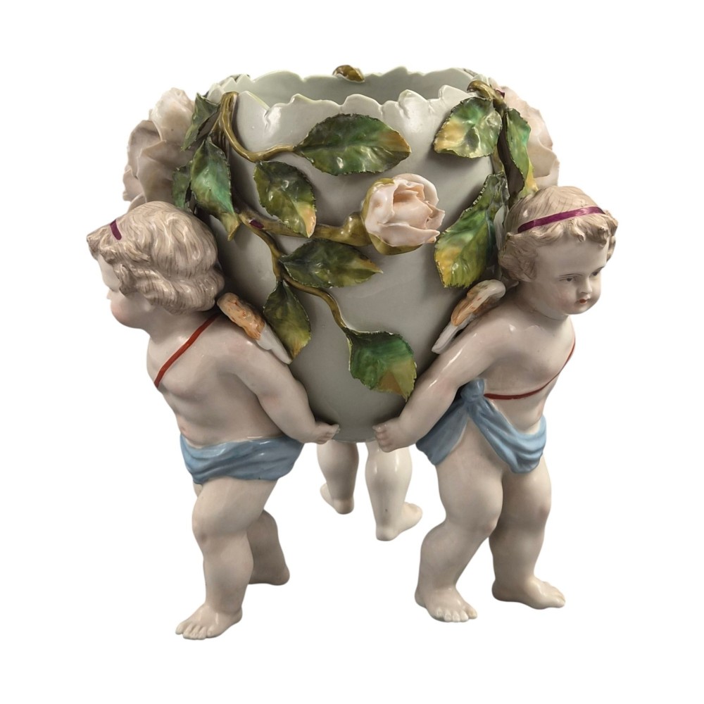 A German Sitzendorf porcelain egg-shaped vase featuring applied green leaves, pale pink roses, and three cherub figures supporting the base. View VI