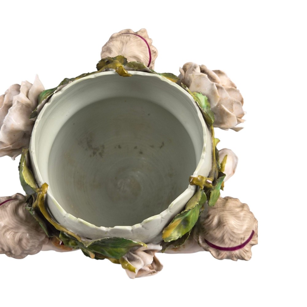 A German Sitzendorf porcelain egg-shaped vase featuring applied green leaves, pale pink roses, and three cherub figures supporting the base. View VII