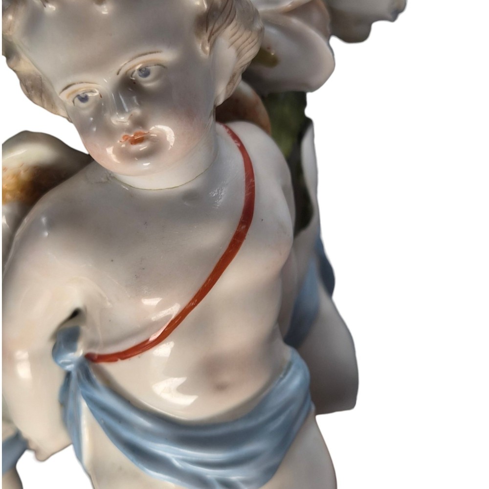 A German Sitzendorf porcelain egg-shaped vase featuring applied green leaves, pale pink roses, and three cherub figures supporting the base. View X