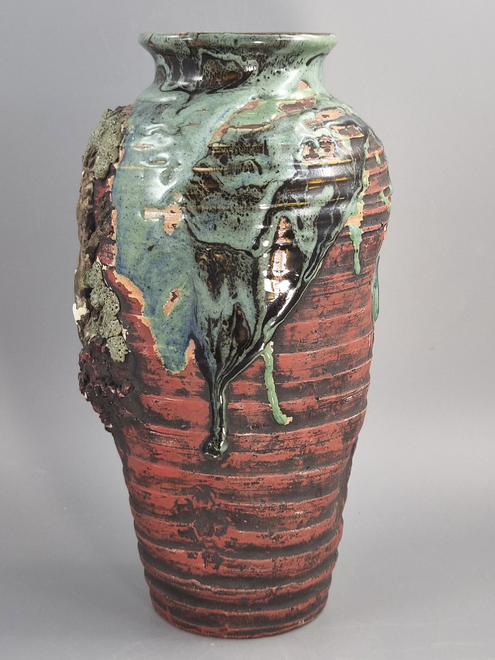 A Japanese Sumida Gawa stoneware vase featuring high-relief sculptures of a stag, waterfall, and tree against a ribbed dark red base with a green drip glaze top rim. View III