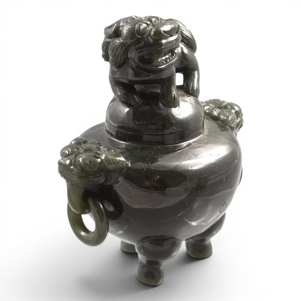 A hand-carved dark green jade tripod censer featuring a foo dog lid finial and lion mask handles with carved loose rings.