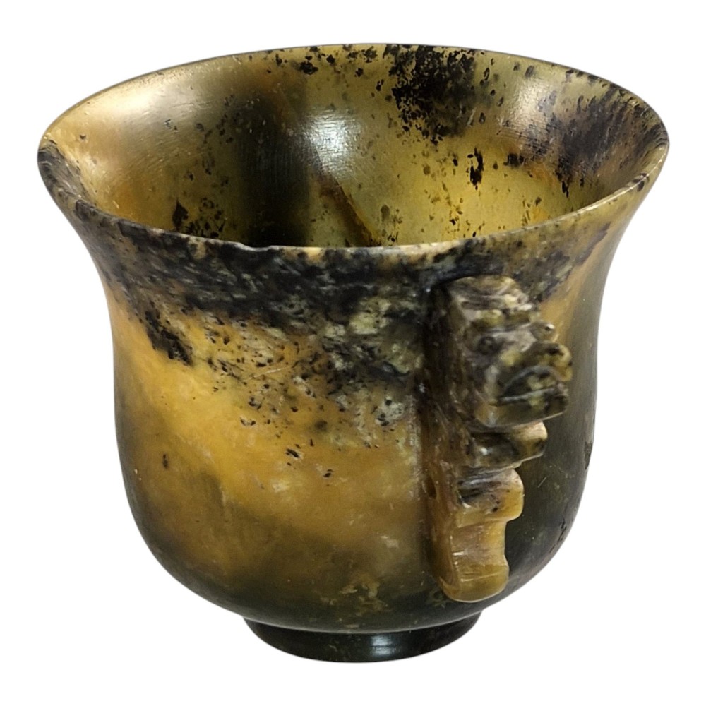 A hand-carved mottled olive-green and dark ochre nephrite jade cup featuring carved handles on either side. View V