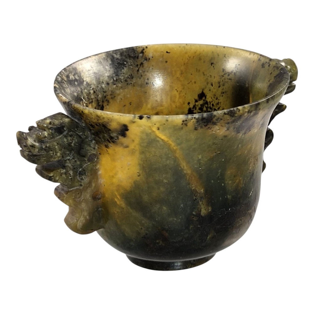A hand-carved mottled olive-green and dark ochre nephrite jade cup featuring carved handles on either side. View VI