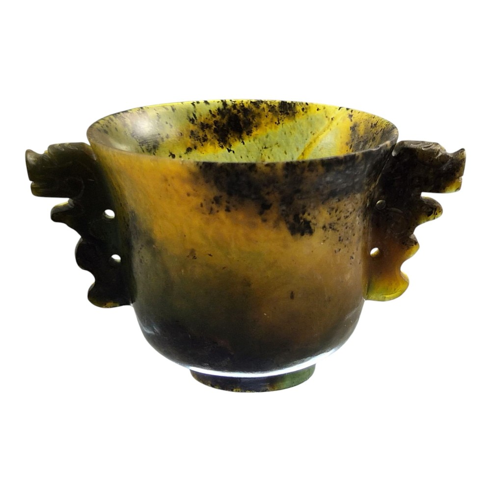 A hand-carved mottled olive-green and dark ochre nephrite jade cup featuring carved handles on either side. View VII