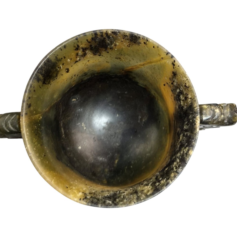 A hand-carved mottled olive-green and dark ochre nephrite jade cup featuring carved handles on either side. View IX