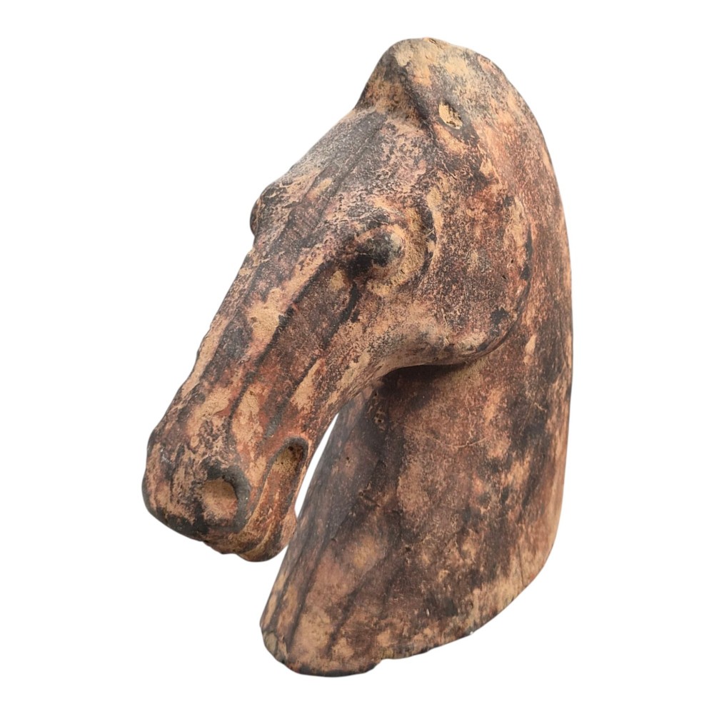 A painted terracotta sculpture depicting the profile of a horse head with earthy red and dark charcoal surface pigments. View IV
