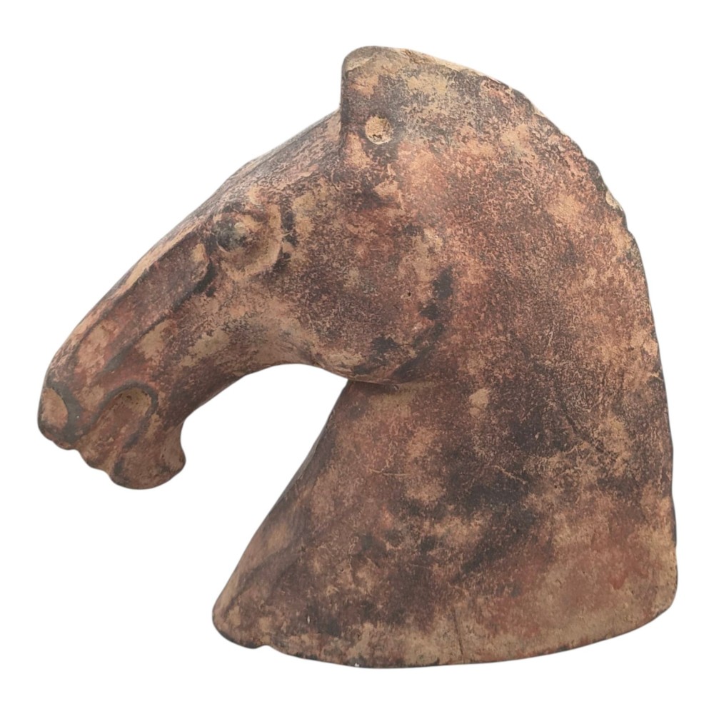 A painted terracotta sculpture depicting the profile of a horse head with earthy red and dark charcoal surface pigments. View V