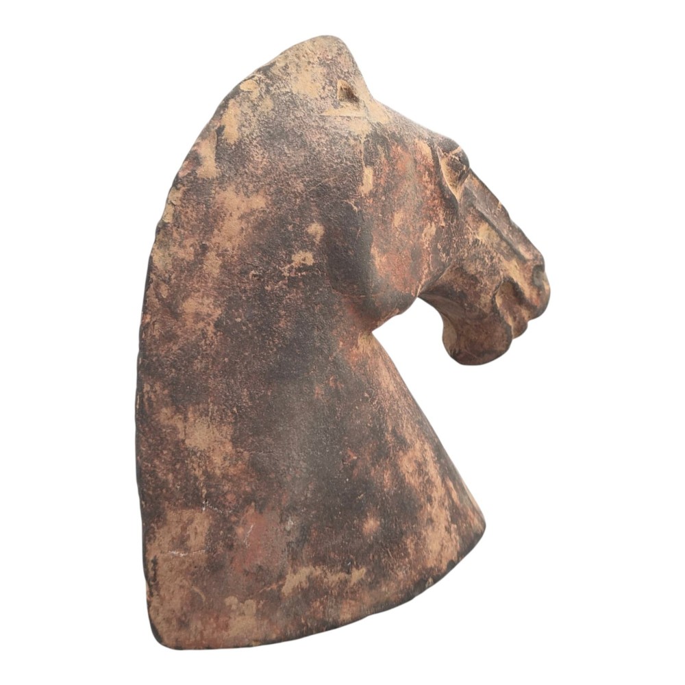 A painted terracotta sculpture depicting the profile of a horse head with earthy red and dark charcoal surface pigments. View VII