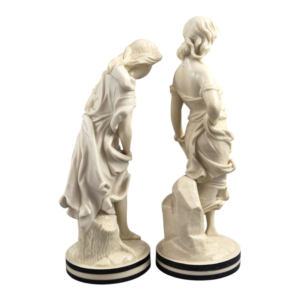 A pair of Victorian cream-glazed porcelain figures depicting classical female forms with flowing drapery set on circular bases. View IV