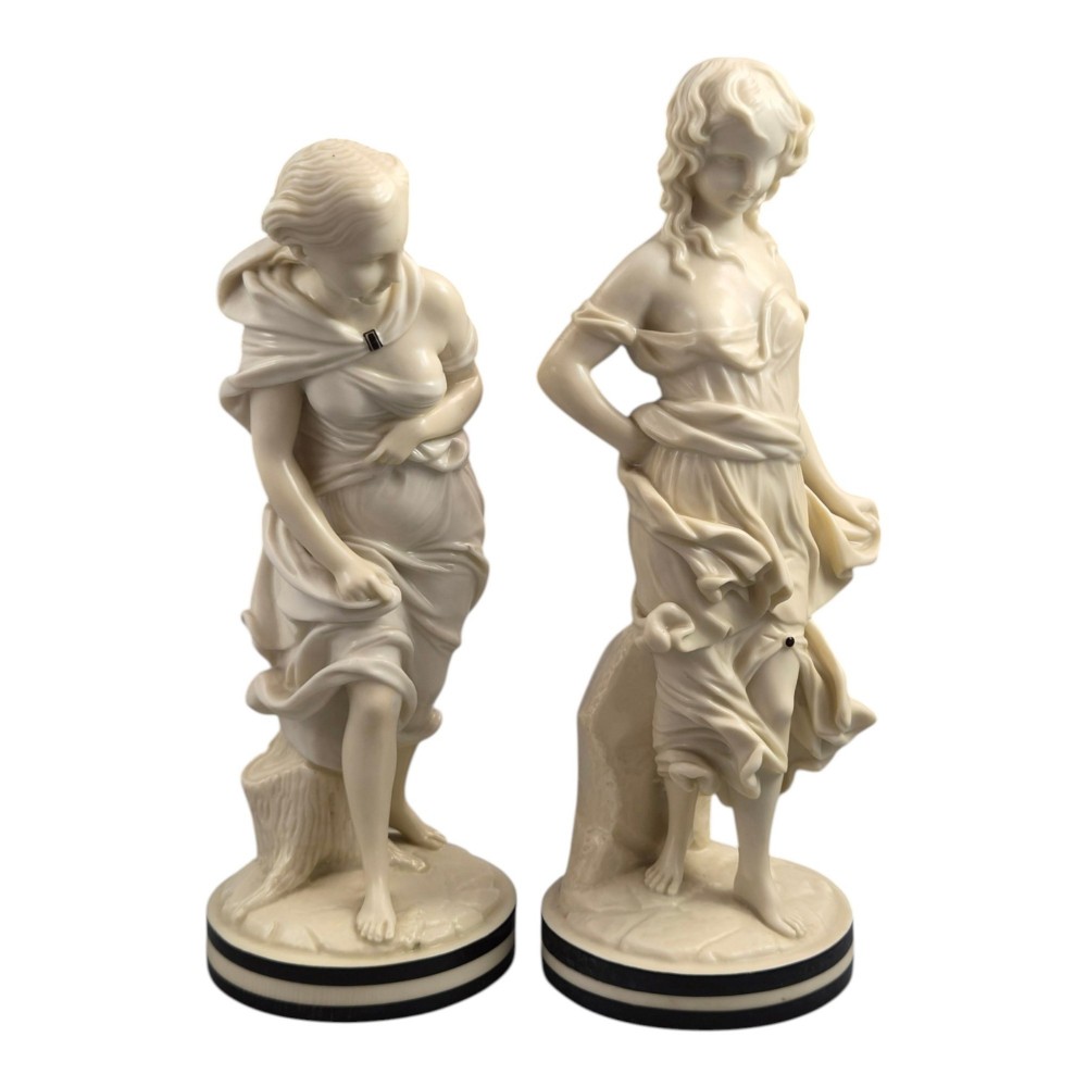 A pair of Victorian cream-glazed porcelain figures depicting classical female forms with flowing drapery set on circular bases. View VI
