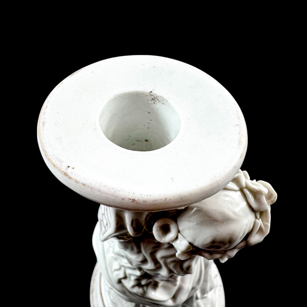 A pair of white glazed porcelain candlesticks featuring sculpted classical female figures holding urn-shaped sconces with gilt trim on circular bases. View IV