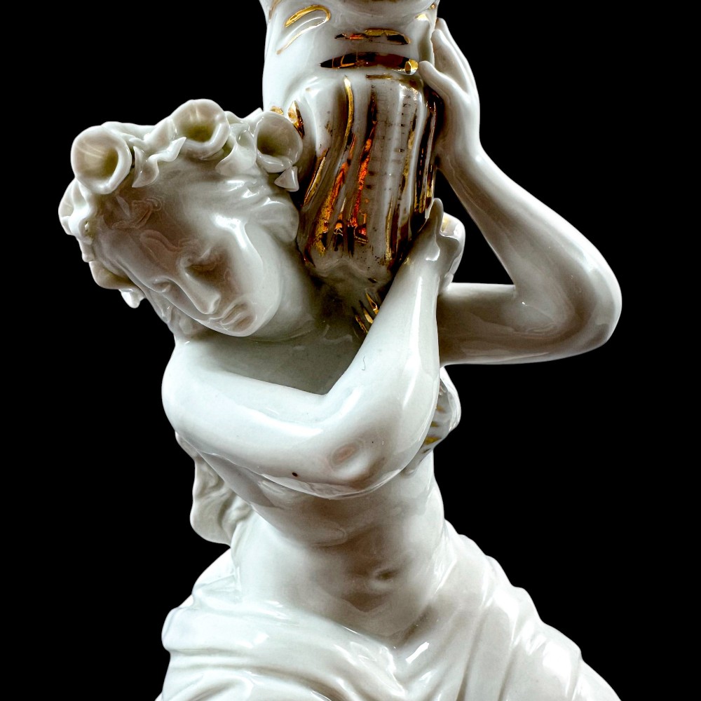 A pair of white glazed porcelain candlesticks featuring sculpted classical female figures holding urn-shaped sconces with gilt trim on circular bases. View XIII