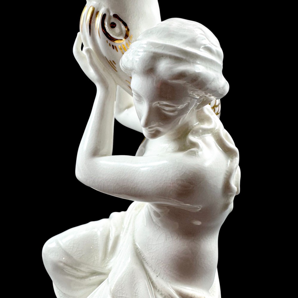 A pair of white glazed porcelain candlesticks featuring sculpted classical female figures holding urn-shaped sconces with gilt trim on circular bases. View XV