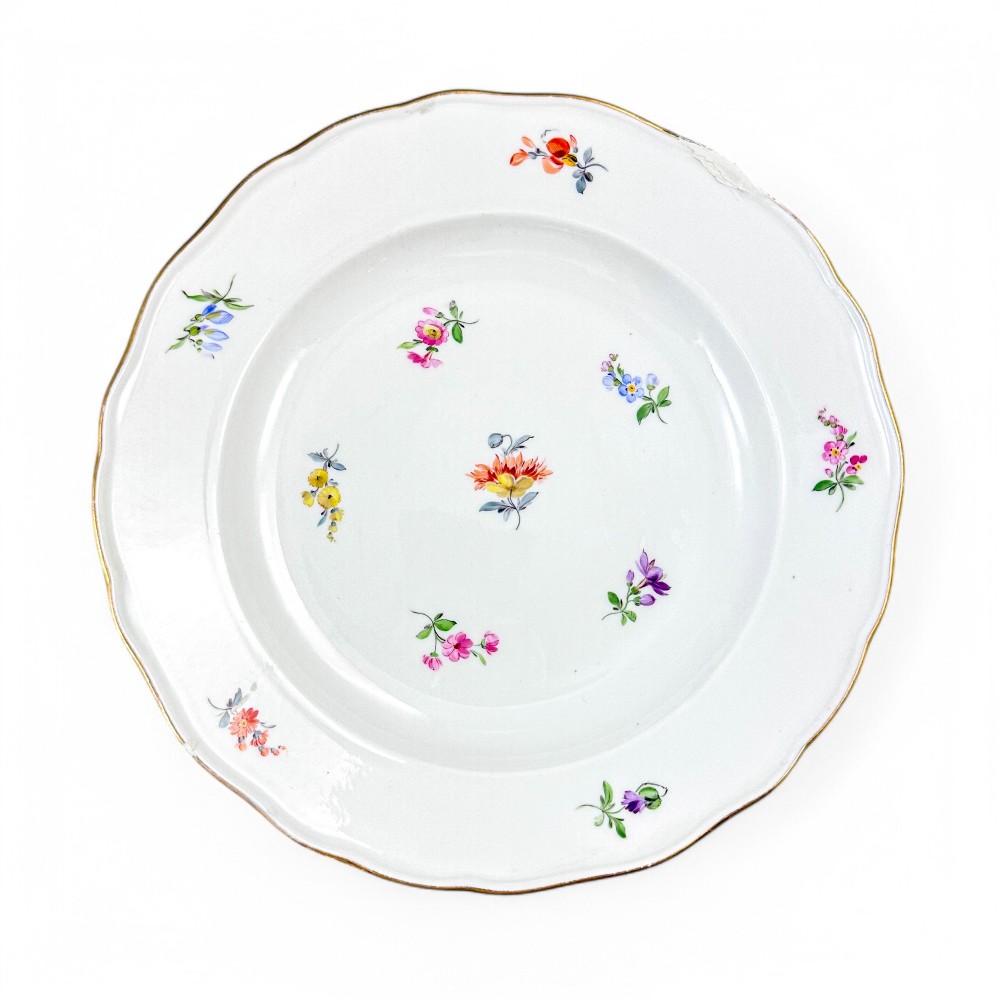 A set of three white hard-paste porcelain plates decorated with hand-painted scattered floral sprigs and scalloped gilded edges. View VI