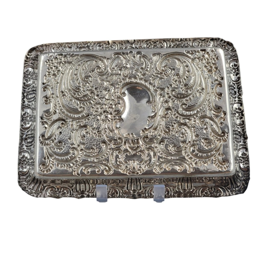 A rectangular Edwardian sterling silver card tray with intricate floral repousse scrollwork detailing, a plain central cartouche, and a raised scalloped rim. View III