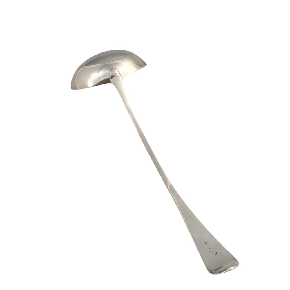 A Georgian sterling silver soup ladle featuring a deep circular bowl, a long curved stem in the Old English pattern, and an engraved crest near the handle tip. View VI