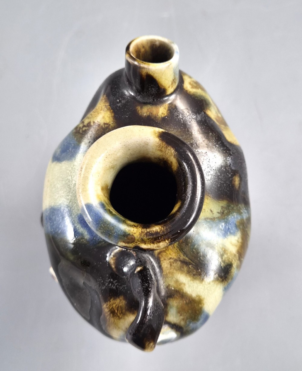A Japanese Sumida Gawa pottery vase featuring an asymmetrical spouted form with a dark flambe drip glaze over a textured red lower body adorned with applied high-relief figures of boys. View XII