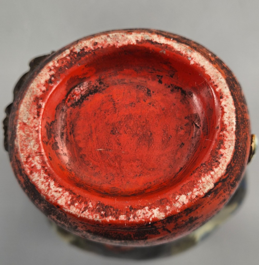 A Japanese Sumida Gawa pottery vase featuring an asymmetrical spouted form with a dark flambe drip glaze over a textured red lower body adorned with applied high-relief figures of boys. View XIII