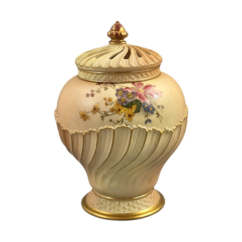 A Royal Worcester blush ivory porcelain pot-pourri jar with a pierced lid, fluted swirled lower body, gold trim, and hand-painted floral motifs. View IV
