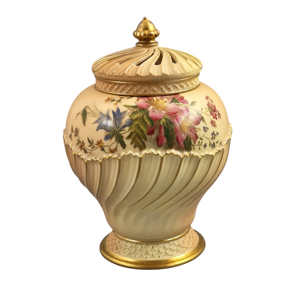 A Royal Worcester blush ivory porcelain pot-pourri jar with a pierced lid, fluted swirled lower body, gold trim, and hand-painted floral motifs. View VI