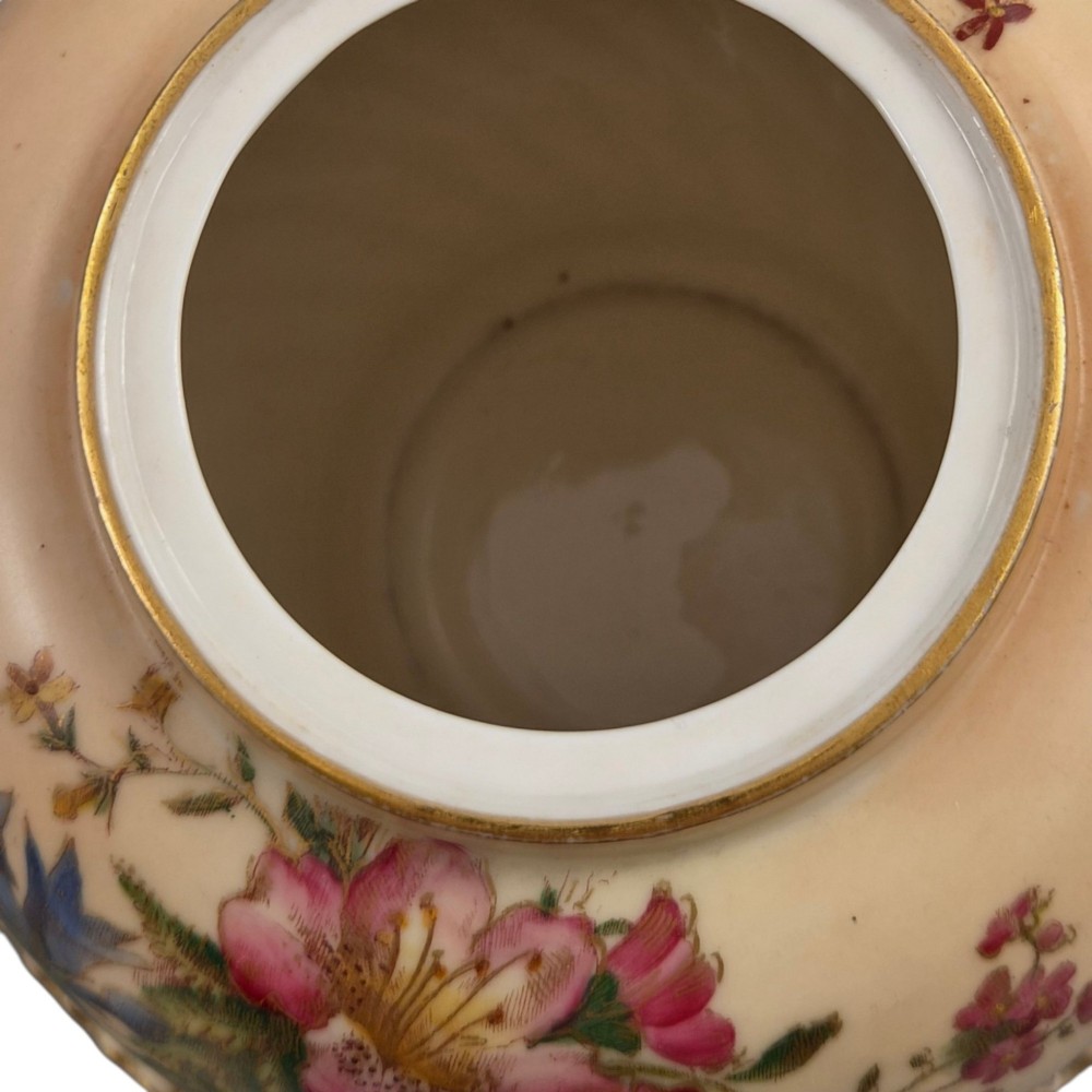 A Royal Worcester blush ivory porcelain pot-pourri jar with a pierced lid, fluted swirled lower body, gold trim, and hand-painted floral motifs. View IX