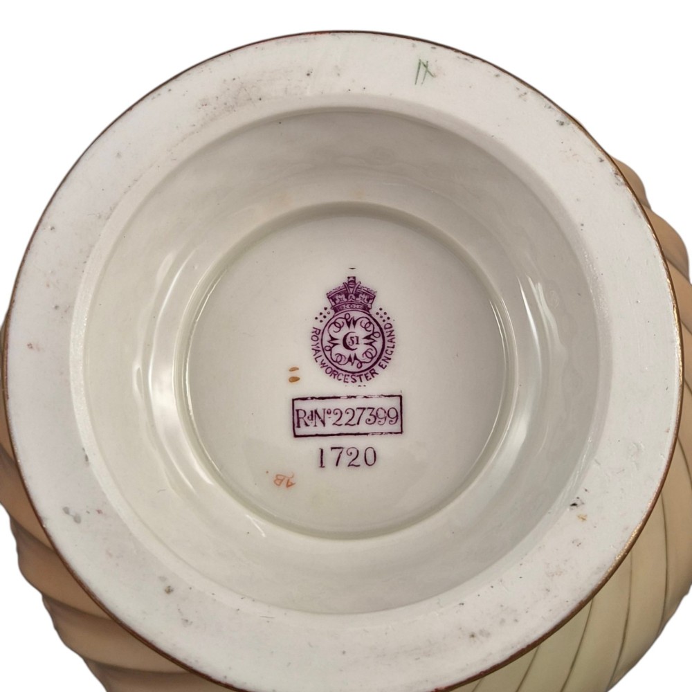 A Royal Worcester blush ivory porcelain pot-pourri jar with a pierced lid, fluted swirled lower body, gold trim, and hand-painted floral motifs. View X