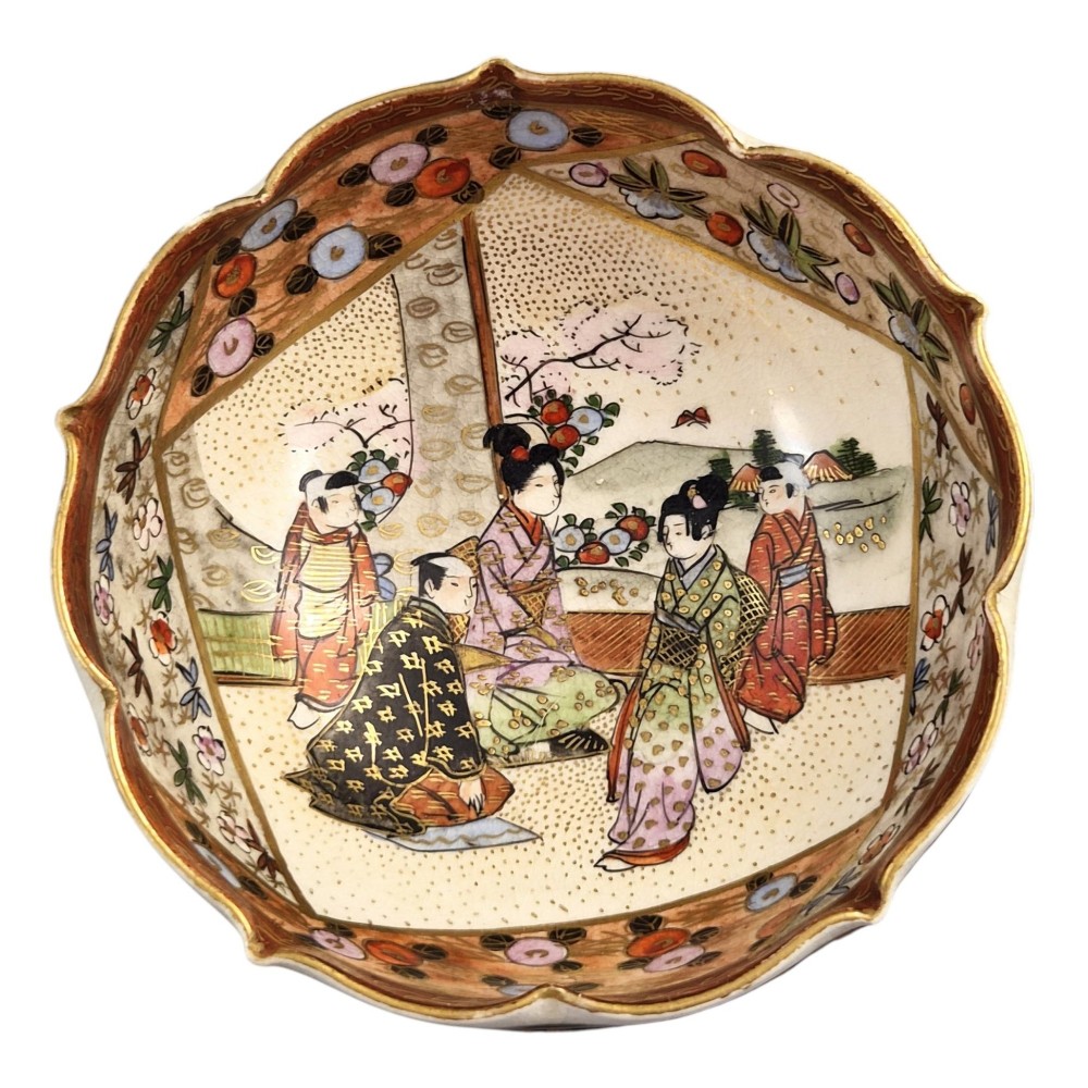 A small lobed Japanese Satsuma ceramic bowl with intricate polychrome floral painting and gold gilding, resting on a carved dark wooden base. View II