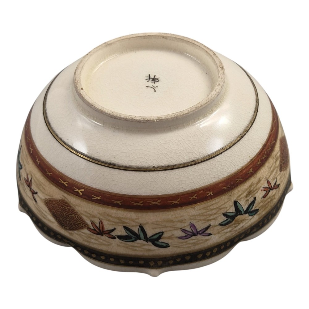 A small lobed Japanese Satsuma ceramic bowl with intricate polychrome floral painting and gold gilding, resting on a carved dark wooden base. View VII