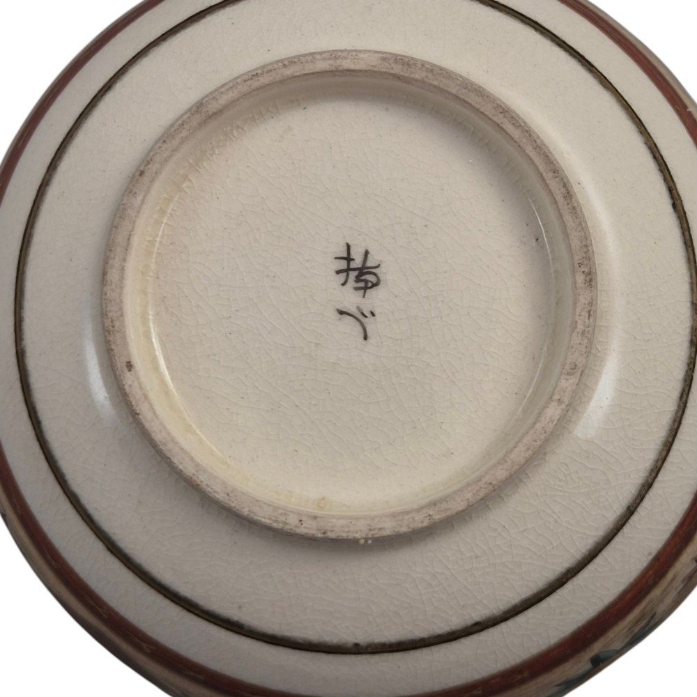 A small lobed Japanese Satsuma ceramic bowl with intricate polychrome floral painting and gold gilding, resting on a carved dark wooden base. View VIII