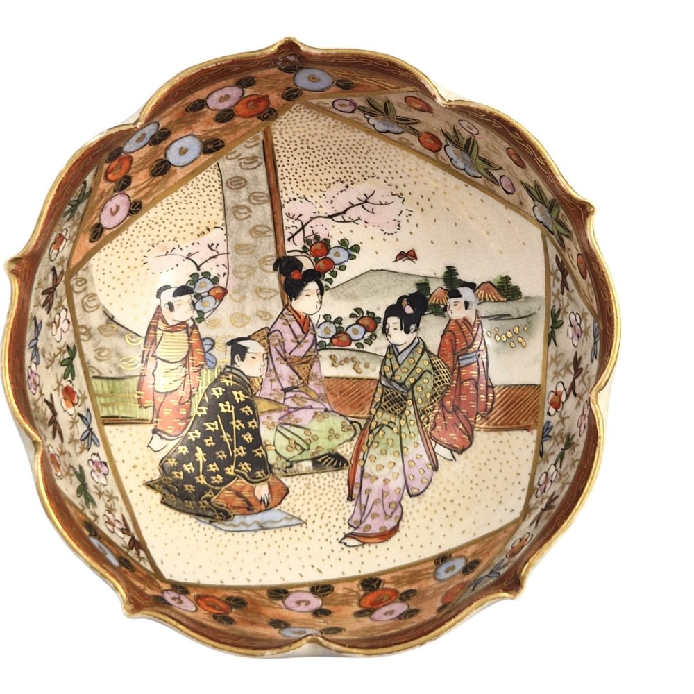 A small lobed Japanese Satsuma ceramic bowl with intricate polychrome floral painting and gold gilding, resting on a carved dark wooden base. View IX