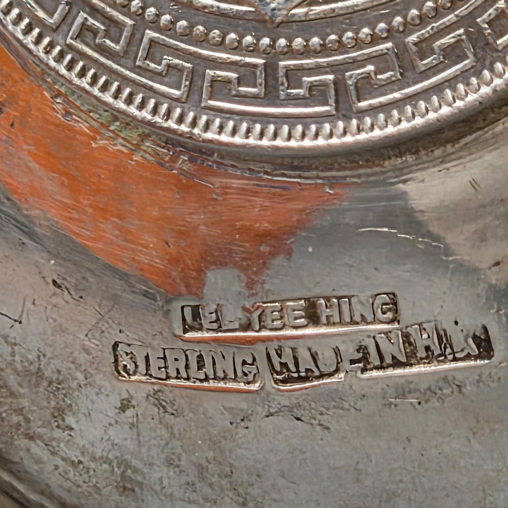 A circular sterling silver dish featuring three cigarette rests on the outer rim and an inset 1899 British Trade Dollar coin in the centre. View V