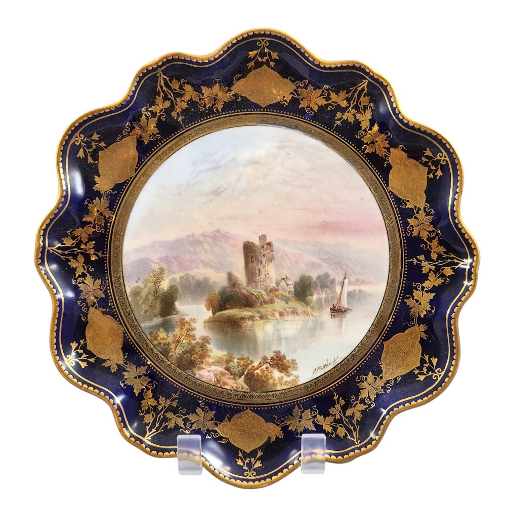 A set of four late nineteenth-century Aynsley porcelain cabinet plates featuring hand-painted landscape scenes surrounded by cobalt blue rims with heavy gold foliage gilding. View V
