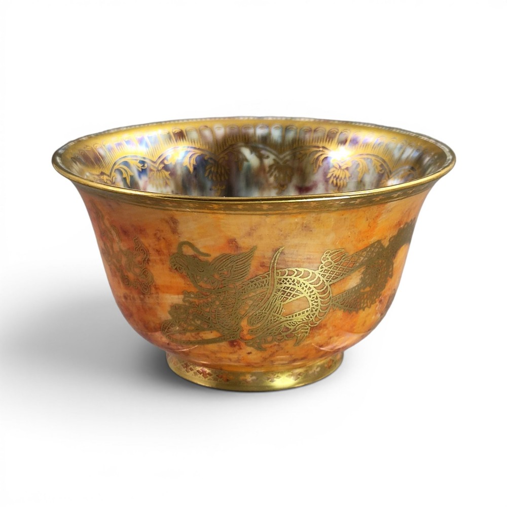 An antique ceramic bowl with a mottled orange lustre glaze on the exterior, decorated with a gold gilded dragon, and a pearlescent interior with a gilded scalloped border.