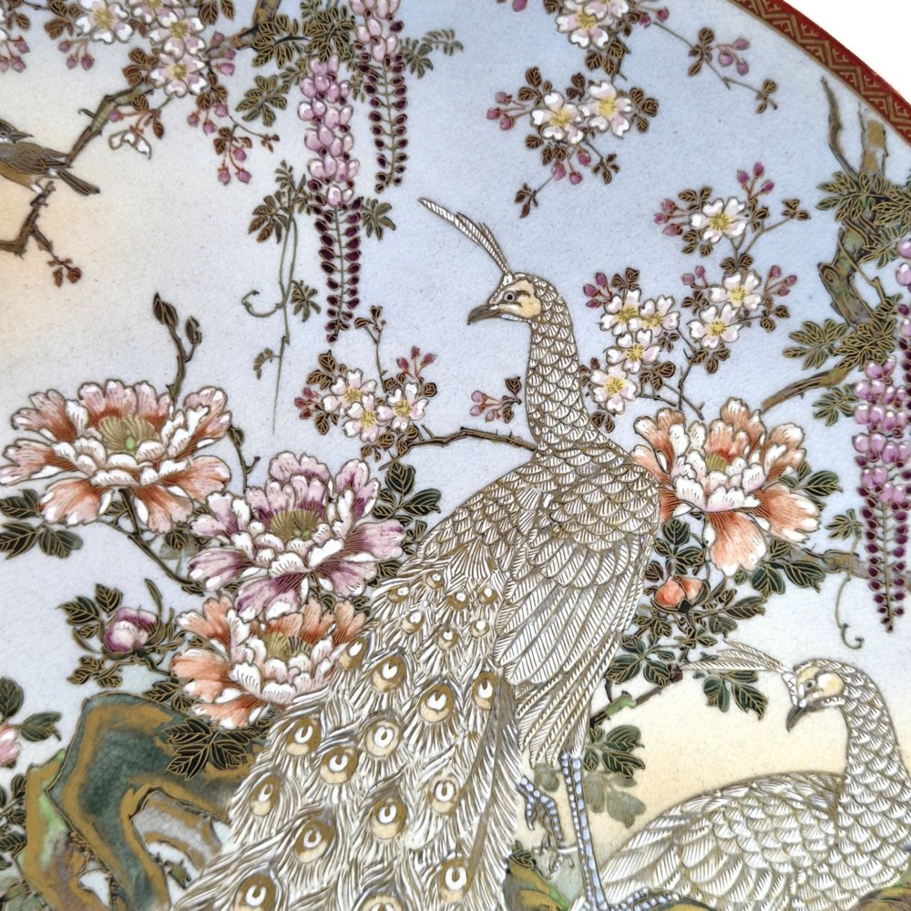 A large circular Japanese Satsuma ceramic charger featuring raised enamel illustrations of peacocks, wisteria, and peonies on a cream crackle glaze background. View III