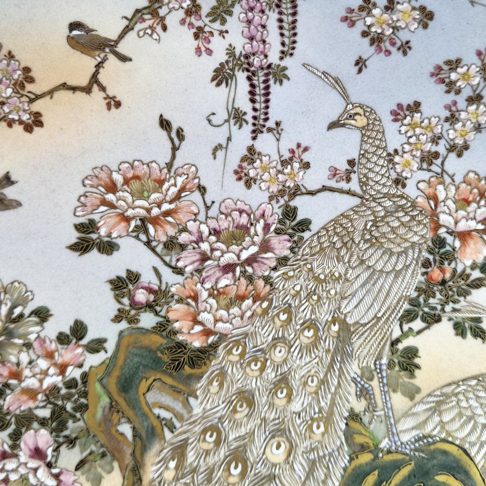 A large circular Japanese Satsuma ceramic charger featuring raised enamel illustrations of peacocks, wisteria, and peonies on a cream crackle glaze background. View V
