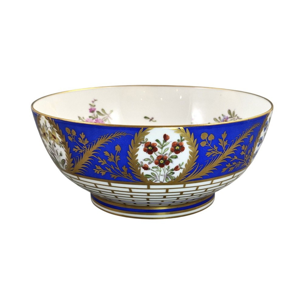 A late 19th-century Samson hard-paste porcelain footed bowl featuring a cobalt blue band with gilded leaf details, hand-painted floral cartouches, and a white brick-patterned base. View X