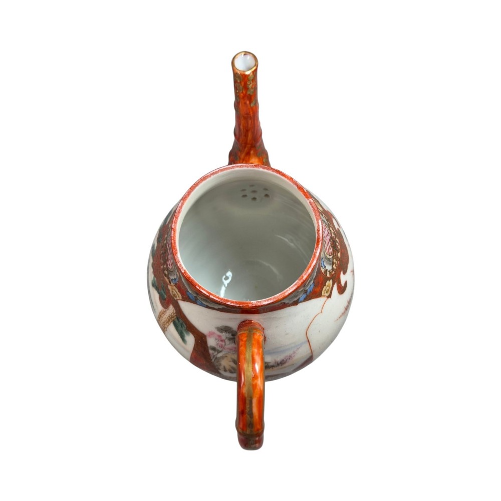 A Japanese Kutani porcelain teapot decorated with iron-red enamel, gilded accents, and hand-painted figurative scenes, seated on a matching pedestal stand. View VI