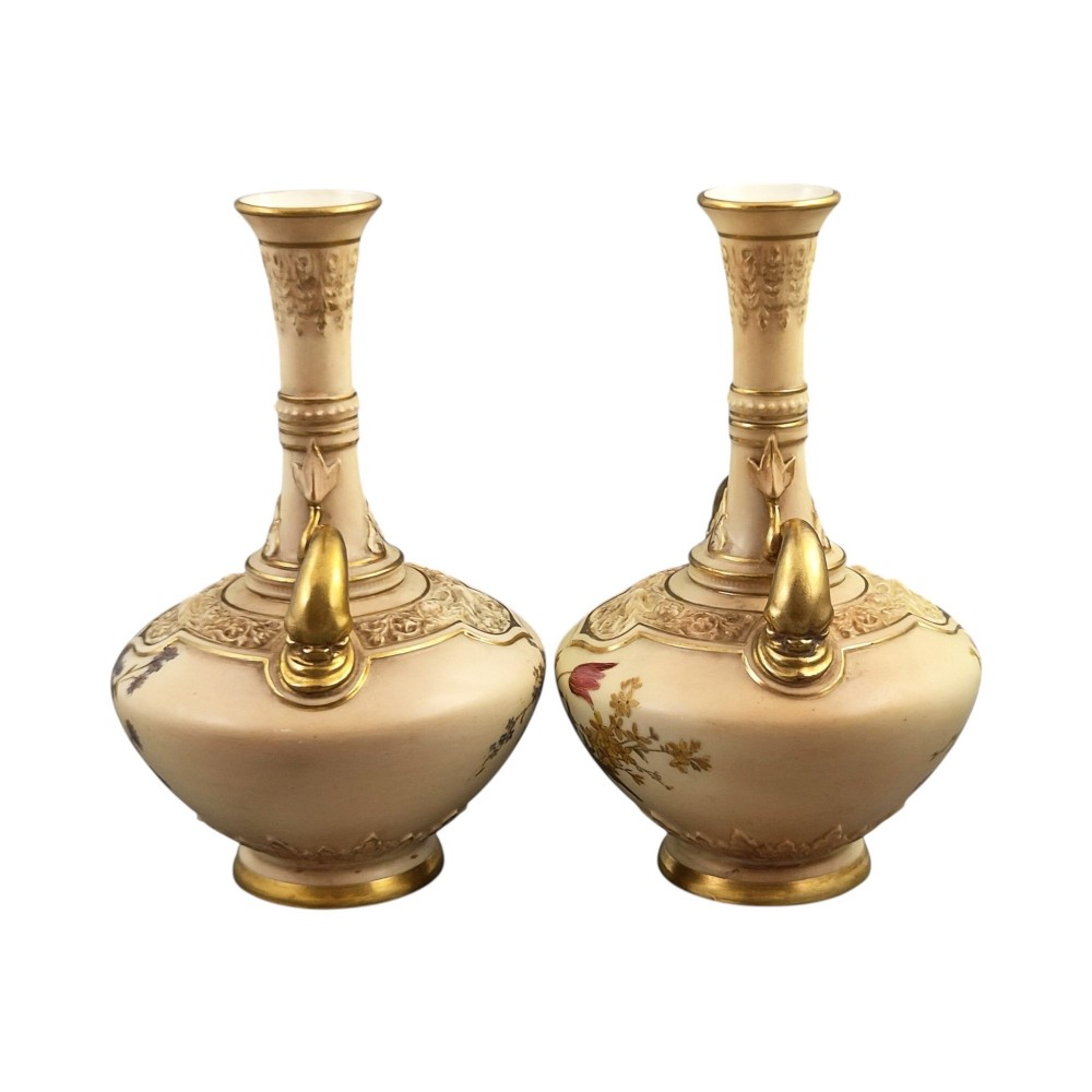 A symmetrical pair of Edwardian Royal Worcester blush ivory porcelain vases featuring gilded dolphin handles, relief-moulded necks, and hand-painted floral decoration. View II