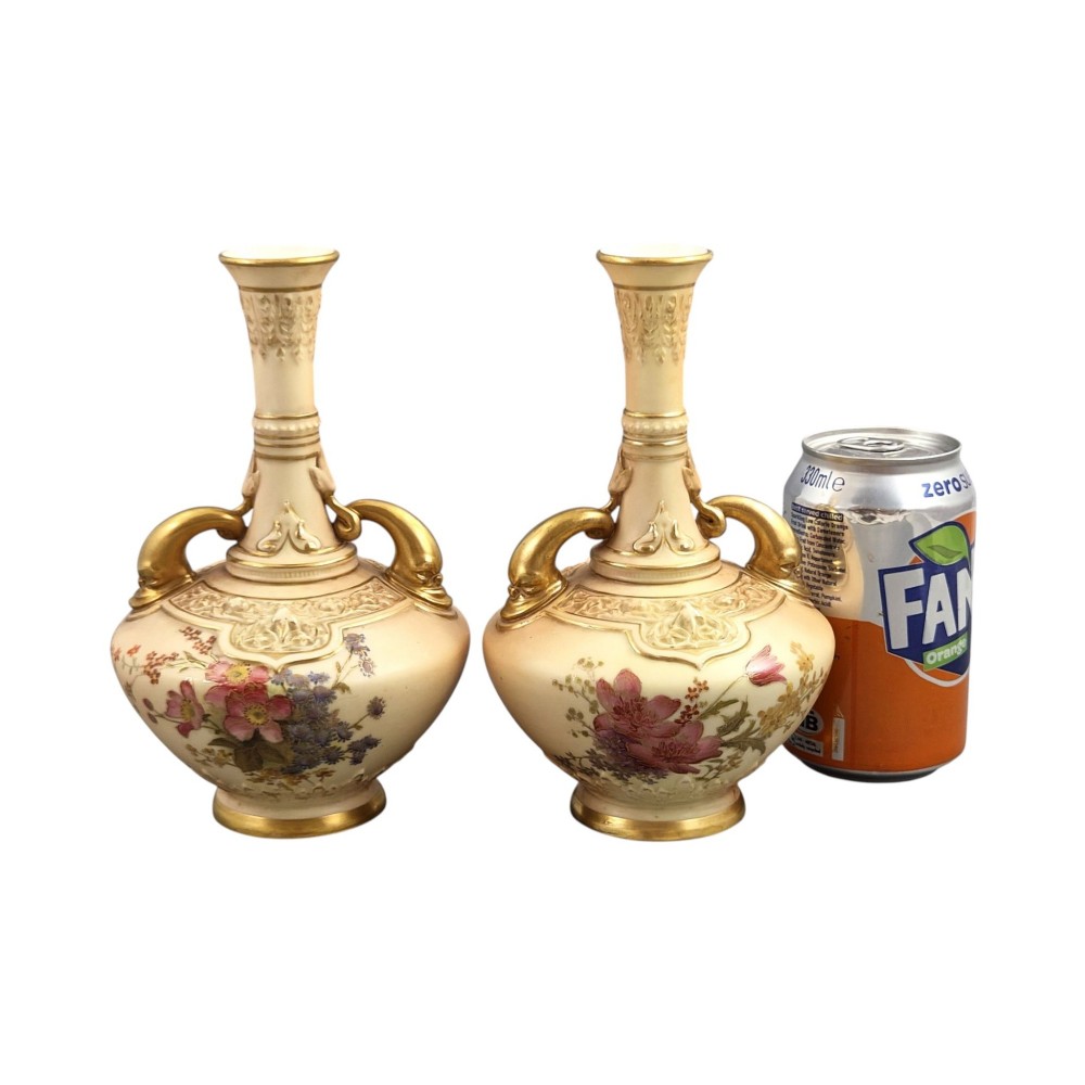 A symmetrical pair of Edwardian Royal Worcester blush ivory porcelain vases featuring gilded dolphin handles, relief-moulded necks, and hand-painted floral decoration. View V