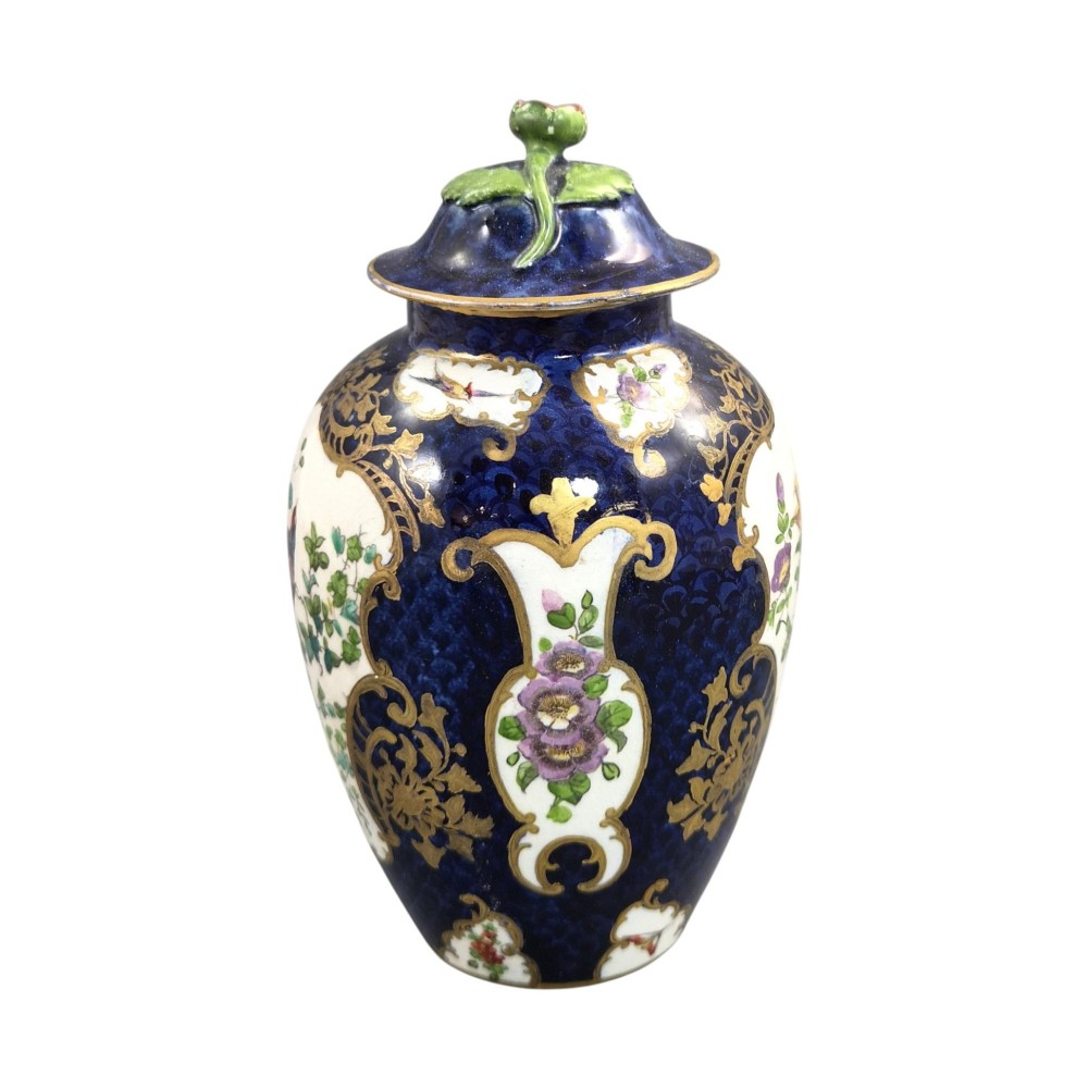 An Edwardian covered ceramic vase featuring a dark scale blue ground with gilded rococo cartouches framing painted floral panels. View III