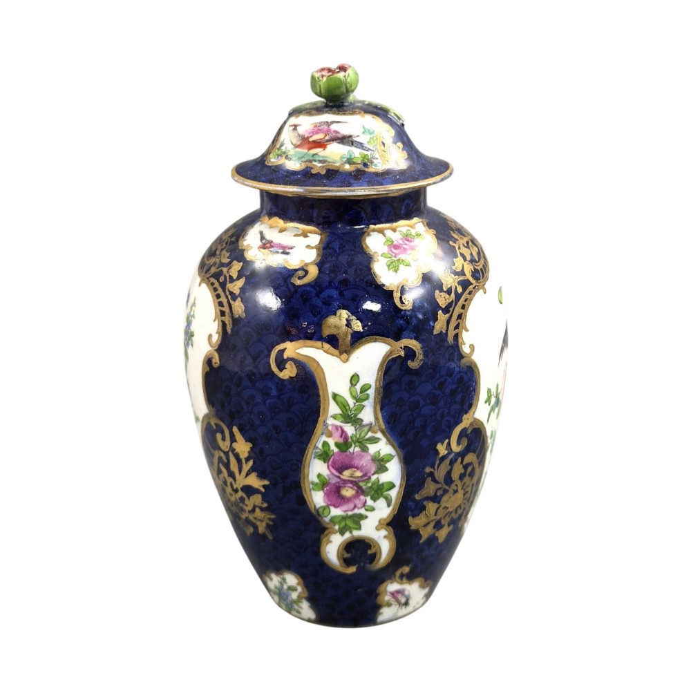 An Edwardian covered ceramic vase featuring a dark scale blue ground with gilded rococo cartouches framing painted floral panels. View V