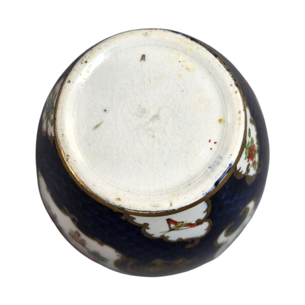 An Edwardian covered ceramic vase featuring a dark scale blue ground with gilded rococo cartouches framing painted floral panels. View VII