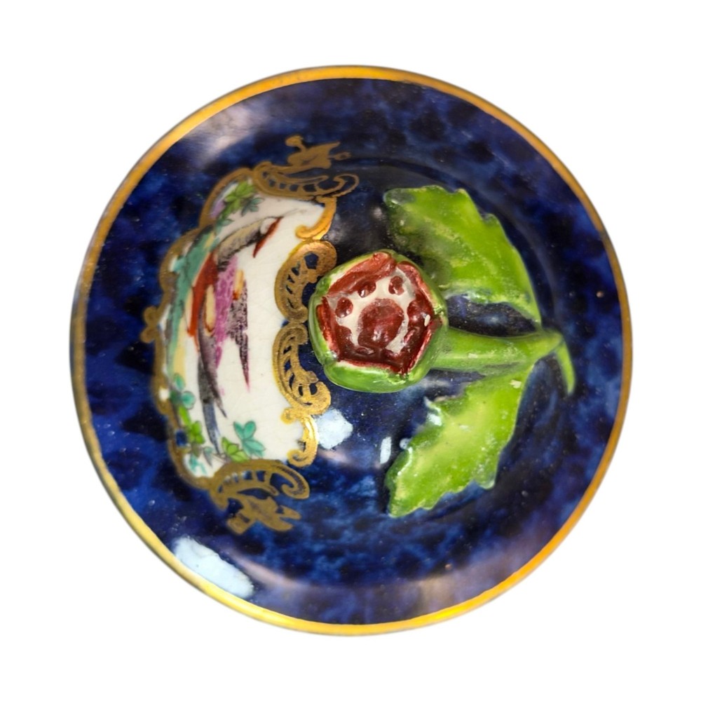 An Edwardian covered ceramic vase featuring a dark scale blue ground with gilded rococo cartouches framing painted floral panels. View IX