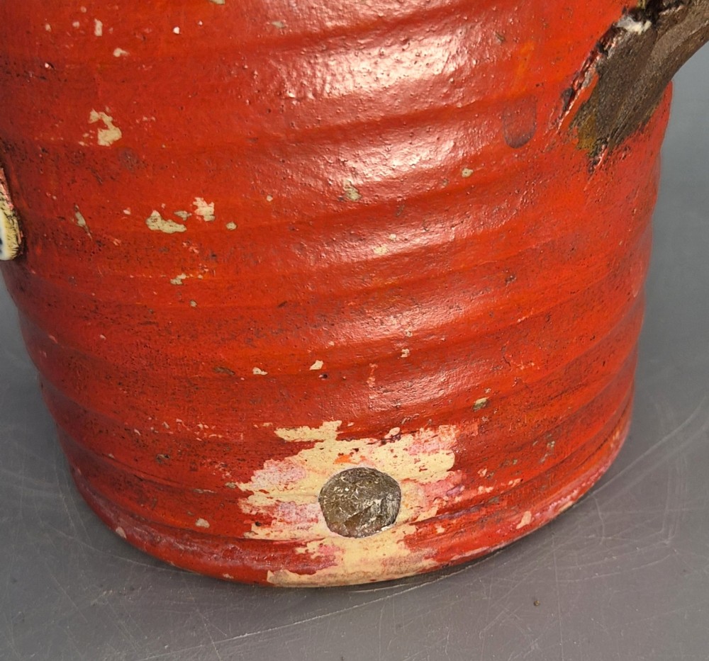 A tall Japanese Sumida Gawa ceramic vase featuring a ribbed red base, applied relief figures of sages on a cliff, and a heavy dark drip glaze around the rim. View VIII