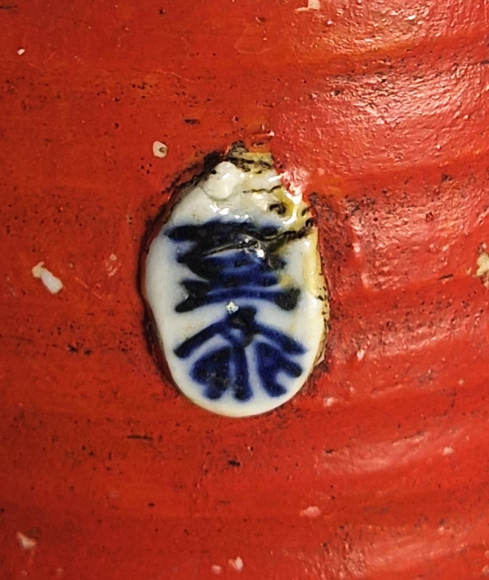 A tall Japanese Sumida Gawa ceramic vase featuring a ribbed red base, applied relief figures of sages on a cliff, and a heavy dark drip glaze around the rim. View IX